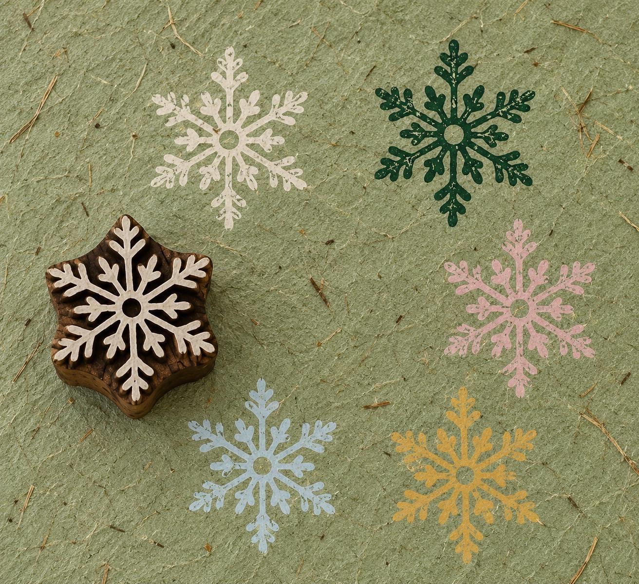 Hand carved Woodland Snowflake wooden printing block with colourful snowflake impressions on textured handmade paper