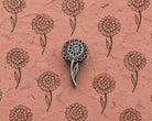 Layered Bloom hand carved wooden printing block with repeated round floral impressions on textured handmade pink paper.