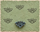 Hand carved Midnight Bat wooden printing block with five bat impressions on handmade green paper.