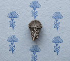 Hand-carved wooden thistle-style flower printing block shown with repeated blue floral prints