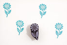 Hand carved wooden daisy botanical block shown with repeated turquoise impressions on white handmade paper.