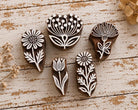 Set of five hand carved wooden botanical printing blocks arranged together on a distressed wooden surface.