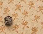 Hand carved wooden Lotus Crest printing block beside repeated lotus flower impressions on textured handmade paper.