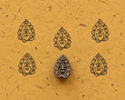 Hand carved wooden Pomegranate Paisley printing block with repeated impressions on textured handmade paper.