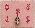 Hand carved wooden Daisy Stem printing block with repeated burgundy floral impressions on pink handmade paper.