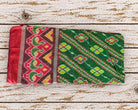 Vintage green Indian silk sari textile laid flat showing its red yellow and burgundy geometric floral pattern and decorative border