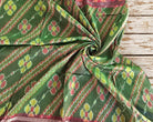 Close-up of vintage green Indian silk showing the detailed ikat-style geometric floral pattern in red yellow and green