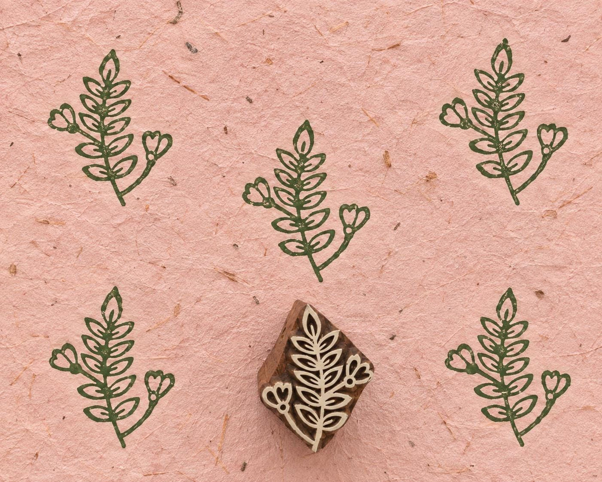Heartbud Sprig 3cm hand carved wooden printing block with repeated green botanical impressions on pink handmade paper.