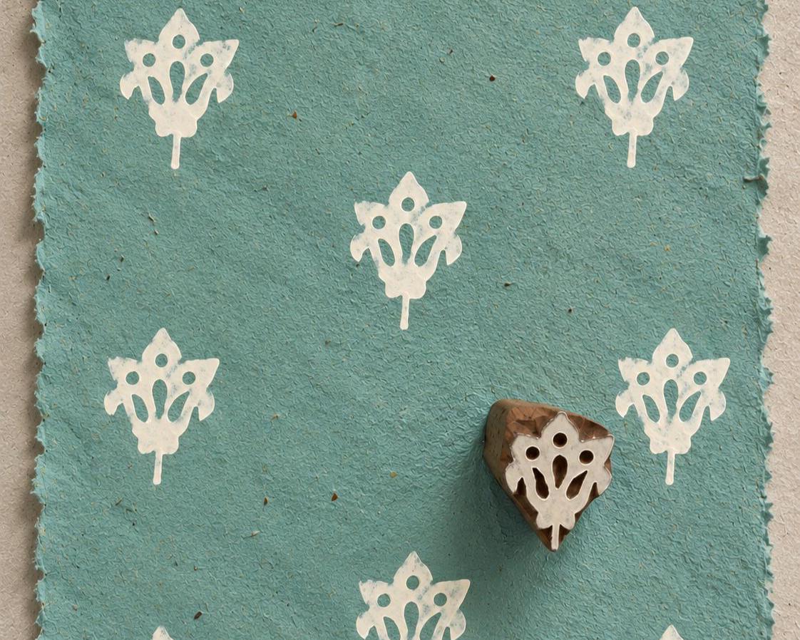 Tribal Blossom 3cm hand carved wooden printing block with repeated white floral impressions on blue handmade paper.