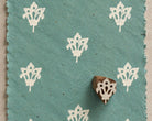 Tribal Blossom 3cm hand carved wooden printing block with repeated white floral impressions on blue handmade paper.