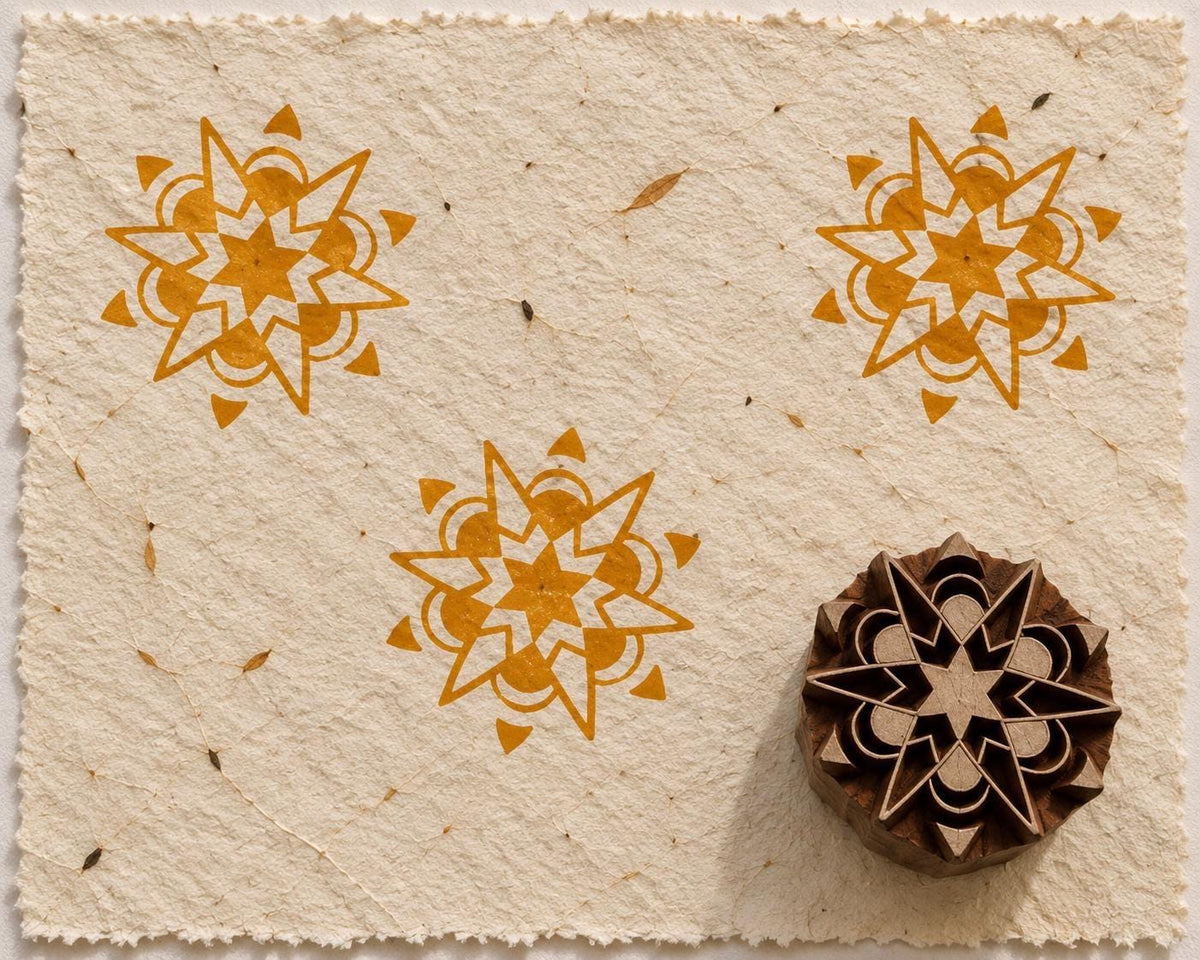 Hand carved Indian wooden printing block with a petal starburst design beside repeated ochre impressions on handmade paper