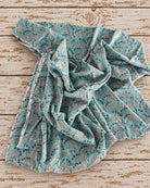 Soft mulmul cotton fabric showing the drape of the aqua blue Indian trailing leaf print
