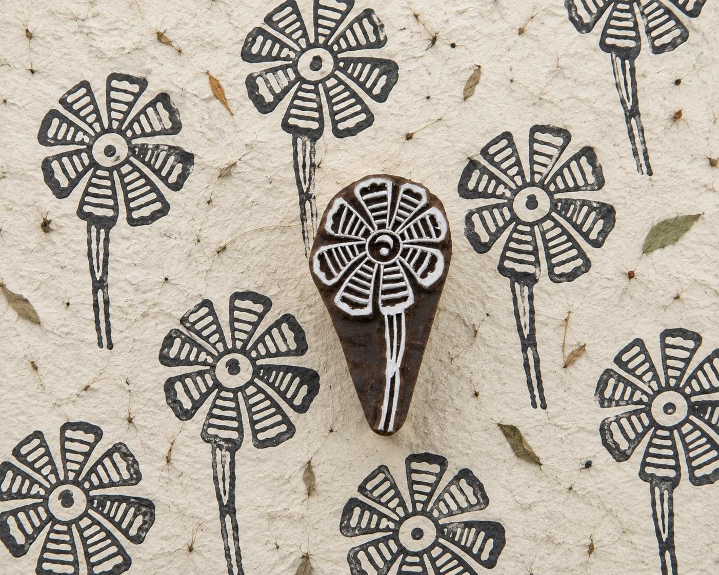 Striped Petal Bloom hand carved wooden printing block with repeated folk flower impressions on handmade paper.