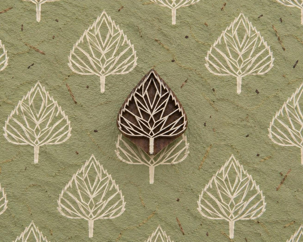 Folk Arrow Leaf hand carved wooden printing block with repeated leaf impressions on handmade green paper.