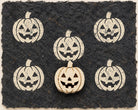 Hand carved Jack-O-Lantern wooden printing block with repeated pumpkin impressions on black handmade paper.