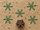 Wooden Christmas printing block with an intricate six-point snowflake made from leafy botanical motifs, shown with green prints.