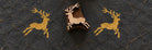 Wooden Christmas printing block featuring a leaping reindeer with antlers, shown with repeated golden prints on dark handmade paper.