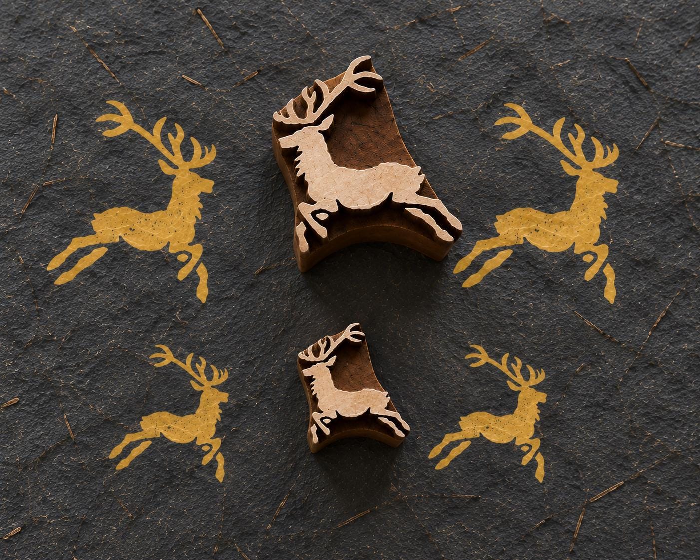 Handmade paper showing repeated brown ink impressions of a whimsical Christmas reindeer set of designs beside its carved wooden printing block.