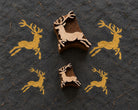 Handmade paper showing repeated brown ink impressions of a whimsical Christmas reindeer set of designs beside its carved wooden printing block.