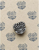 Hand-carved wooden dandelion-style flower printing block with repeated botanical prints on handmade paper