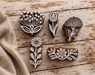 Five hand-carved wooden printing blocks featuring four flower designs and one decorative floral border