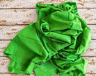 bright lime green vintage sari fabric draped to show its soft texture and colourful woven edge