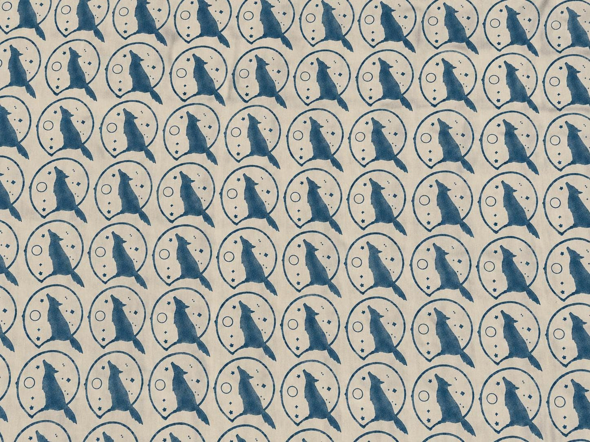 Repeating indigo wolf, moon and stars pattern on cream cotton fabric