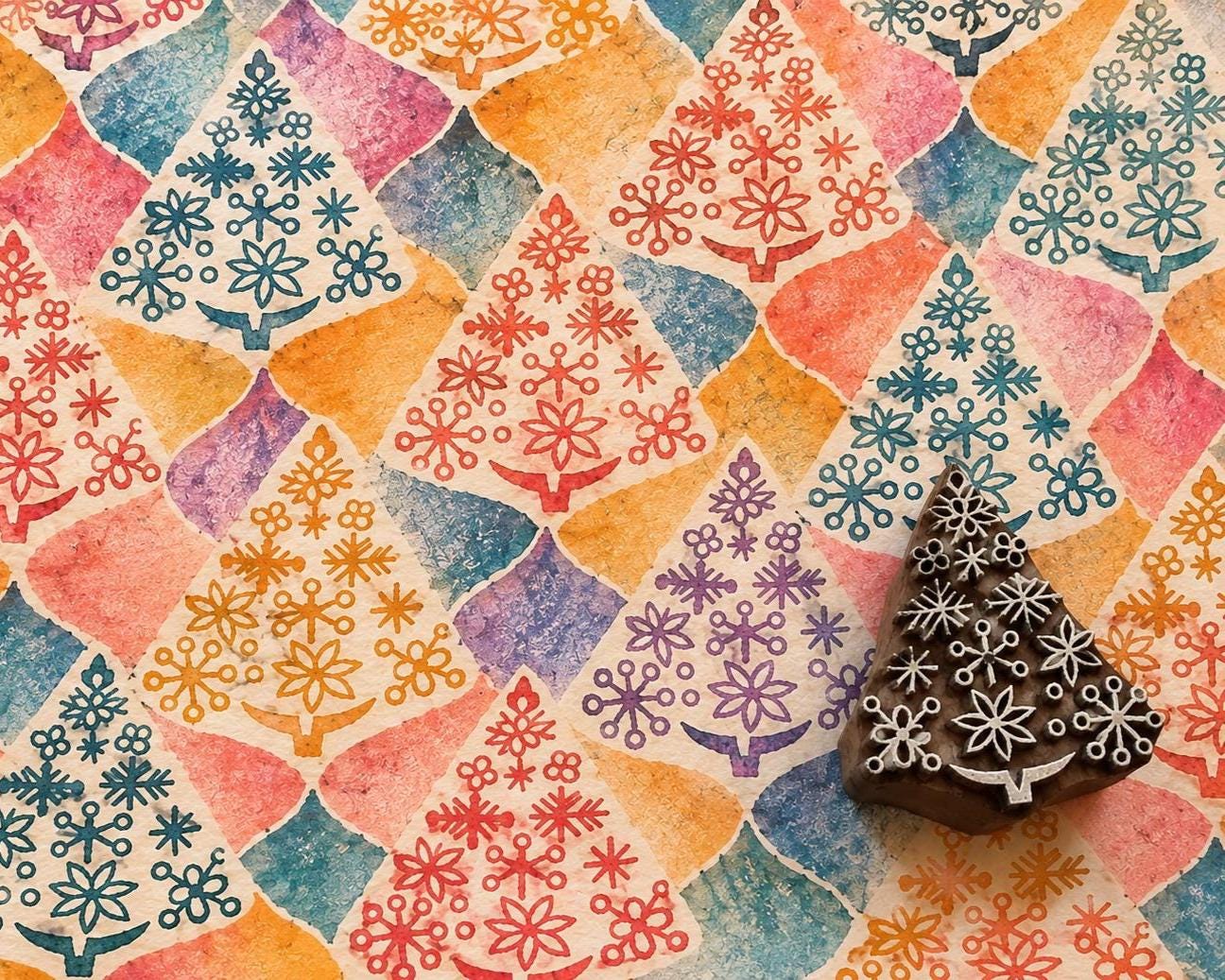 Hand carved Indian wooden Christmas tree printing block filled with snowflake and geometric motifs, shown with colourful repeated tree impressions on handmade paper