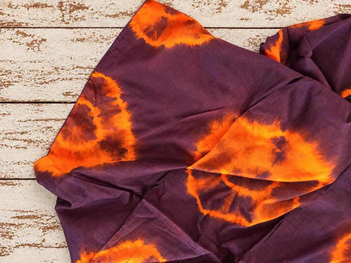 Draped vintage sari silk showing irregular burnt orange tie-dye patterns and a soft finish