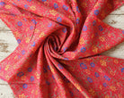 Draped coral-red vintage sari silk showing the small multicoloured floral pattern and soft folds.