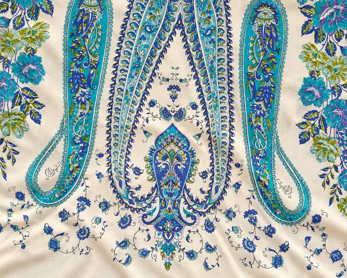 Detailed view of a symmetrical turquoise and blue paisley ornament with small floral motifs.