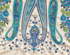 Detailed view of a symmetrical turquoise and blue paisley ornament with small floral motifs.
