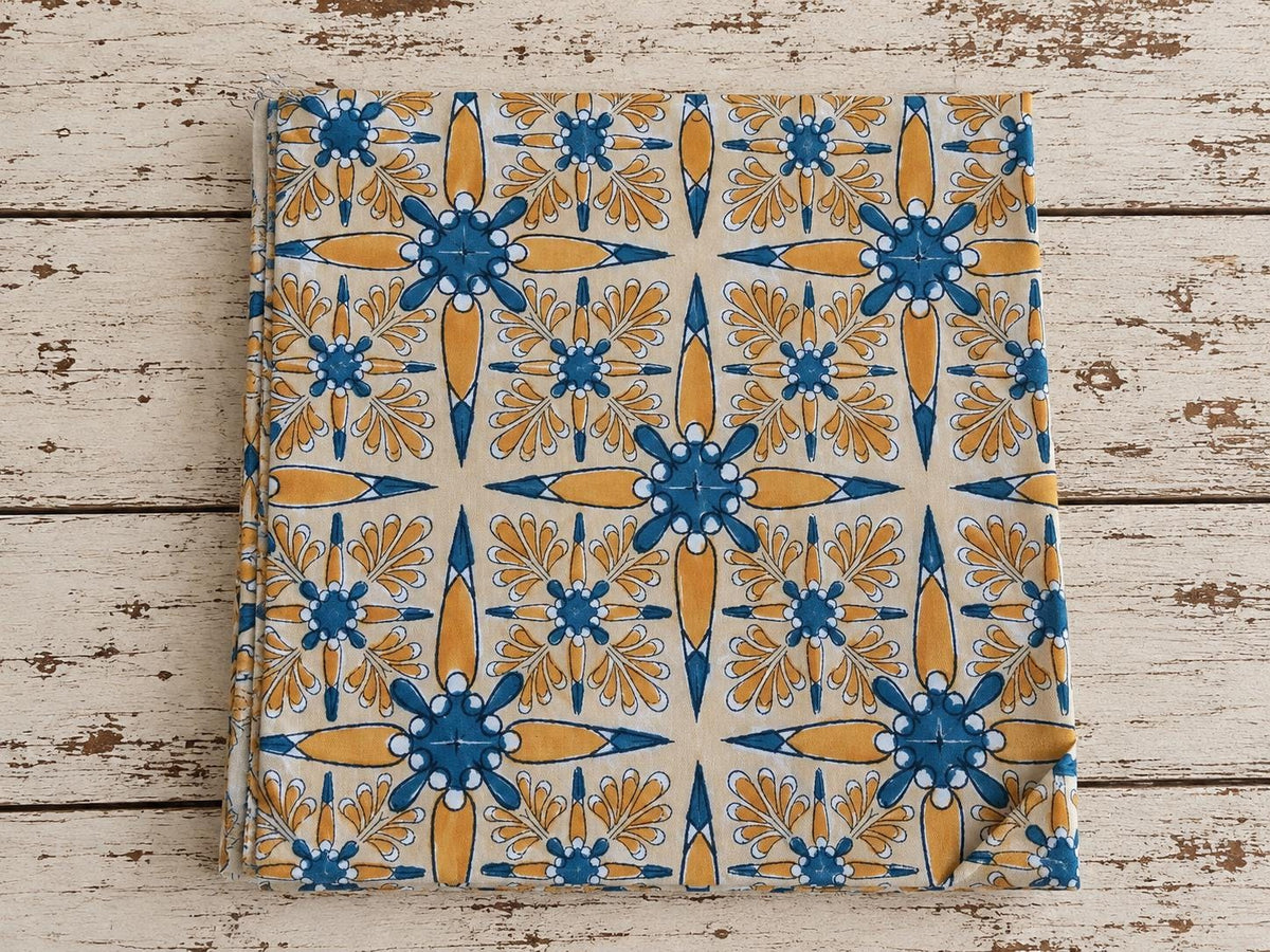 Folk Bloom hand block printed cotton fabric folded on a rustic wooden surface