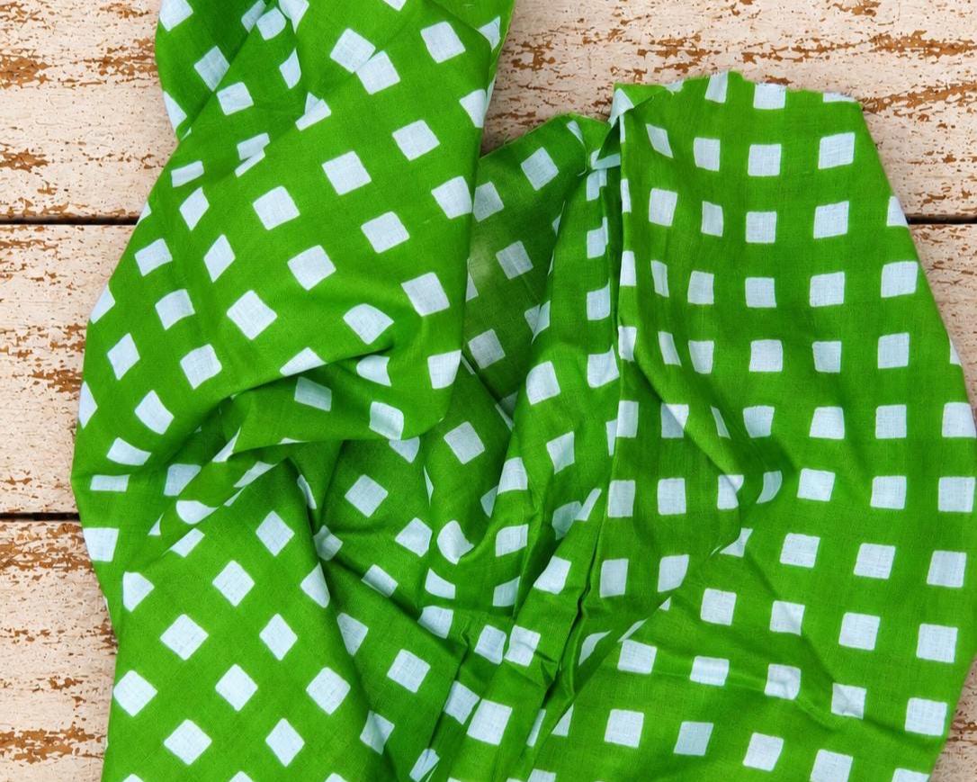 Bright green and white checked fabric draped to show its pattern and natural folds.