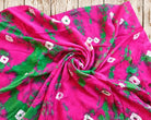 Close-up of soft pink and green vintage sari fabric arranged in a spiral to show its flowing texture and irregular tie-dye pattern.