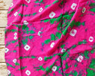 Pink and green vintage sari textile with scattered white motifs and varied tie-dye markings, spread out to show the pattern.