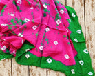 Bright pink vintage sari fabric with green tie-dye patches and white motifs, displaying the distinctive colours and pattern.
