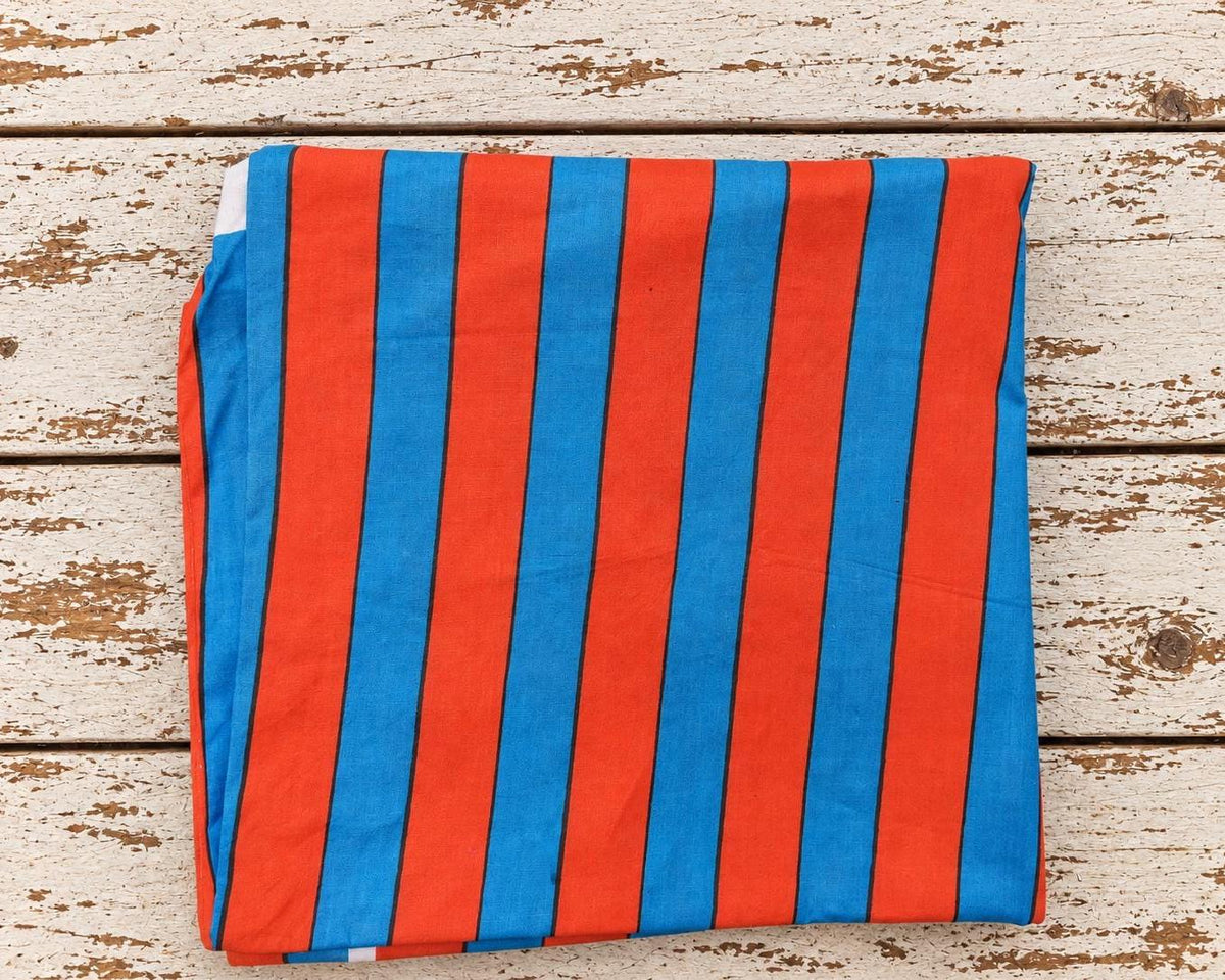 Draped red and blue striped lightweight cotton fabric showing its bold graphic pattern