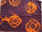 Vintage sari silk remnant opened out to show its orange circular motifs on a plum background