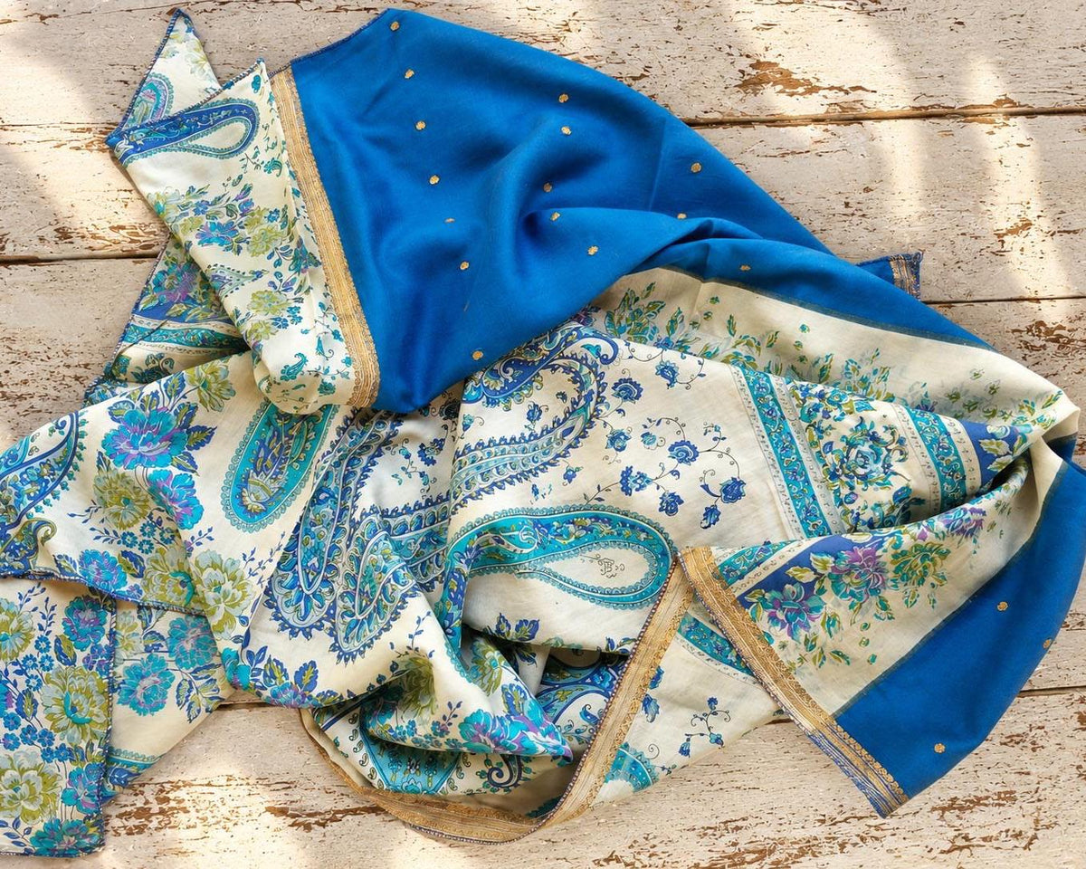 Draped blue and ivory silk sari fabric displaying its contrasting floral and paisley designs.