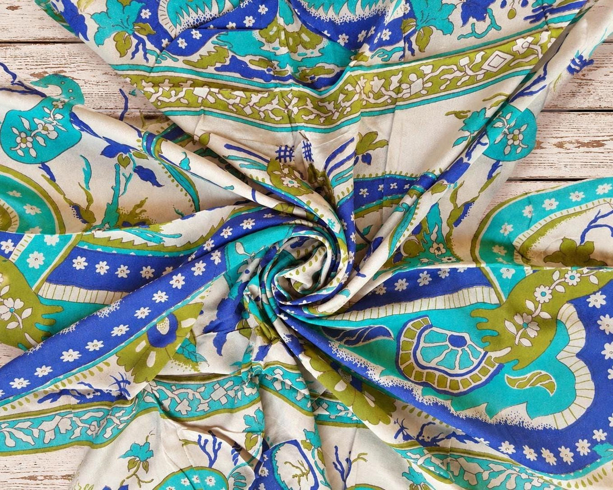 Close-up of vintage silk featuring turquoise, blue and olive paisley patterns on ivory.