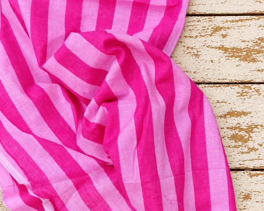 Draped hot pink and light pink striped lightweight cotton showing the fabric texture and pattern