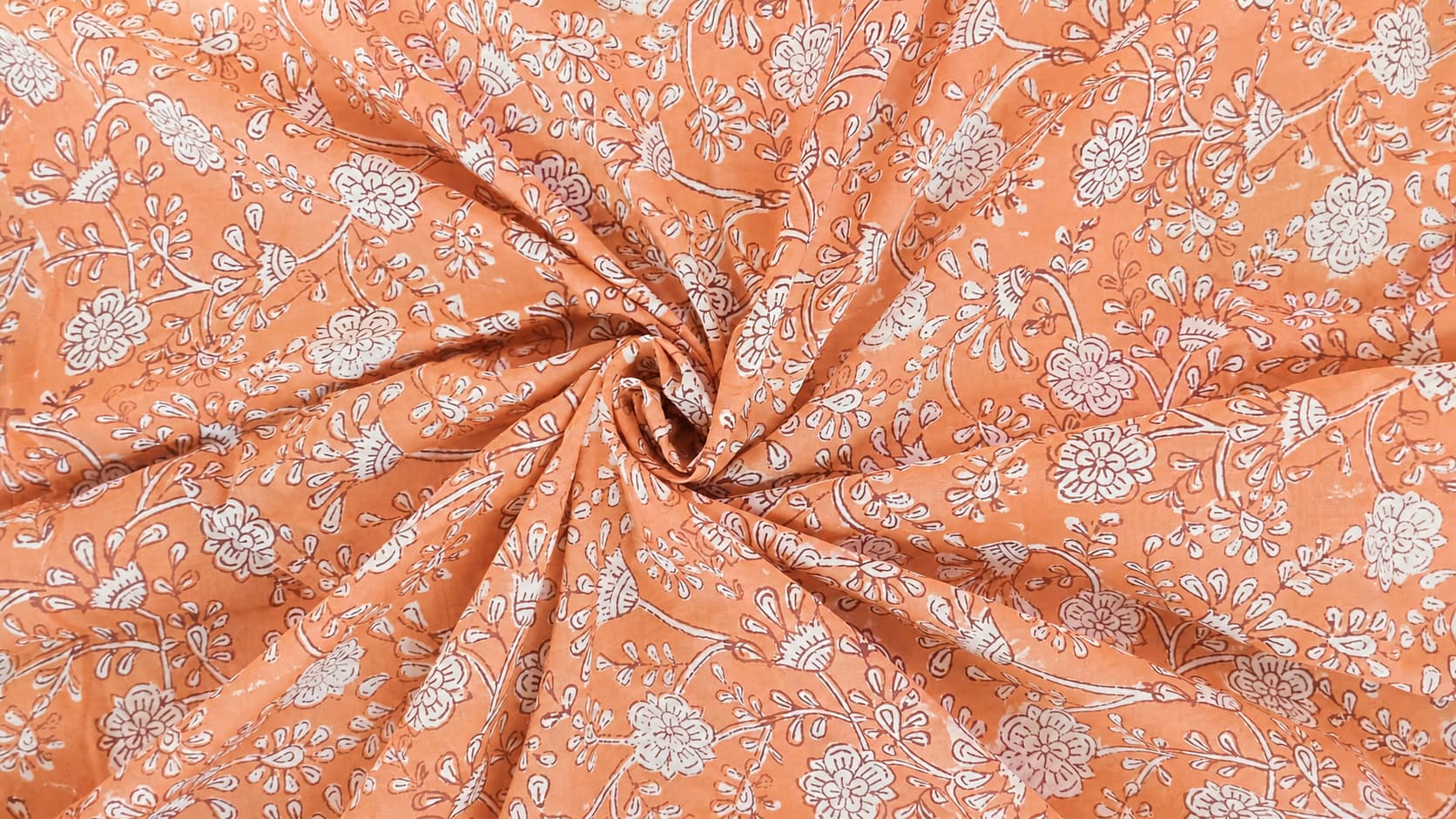 Apricot floral block printed cotton fabric showing drape and texture