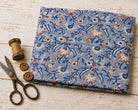 Folded hand block printed cotton fabric with ivory and orange wildflowers on a powder blue background
