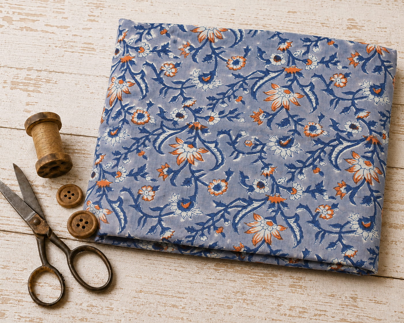 Folded hand block printed cotton fabric with ivory and orange wildflowers on a powder blue background
