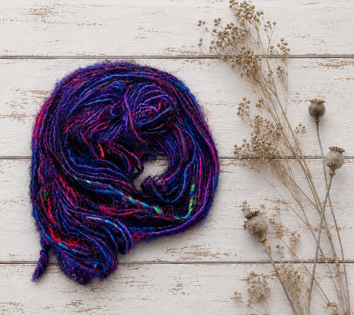 Jewel Tones recycled sari silk yarn in vibrant purple, pink and blue shades arranged in a coiled skein.
