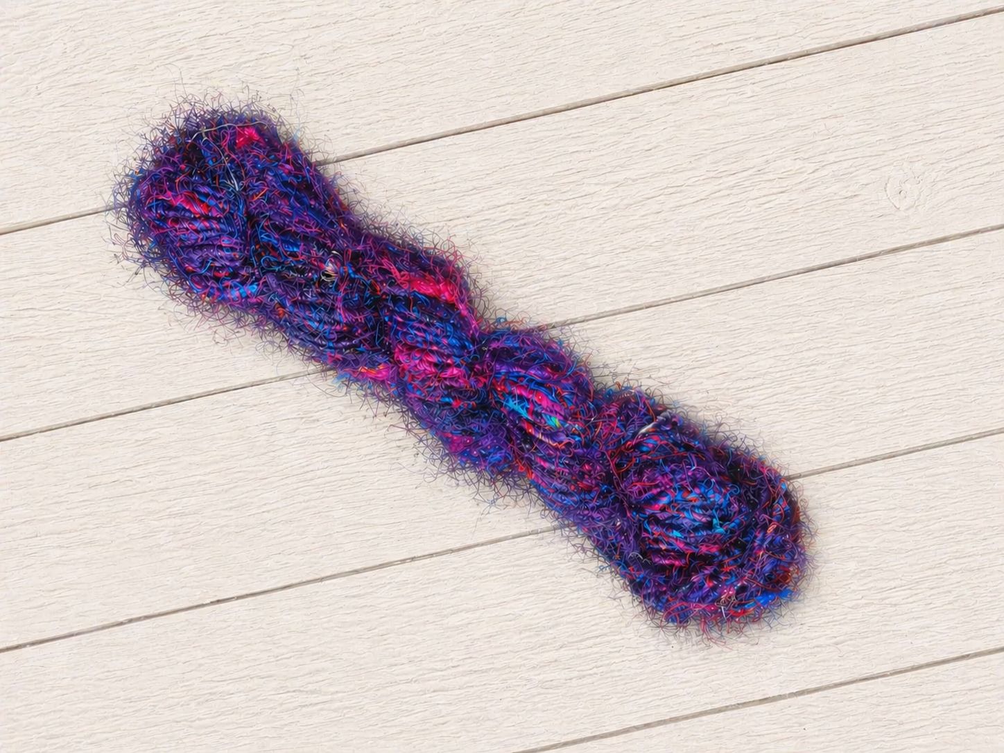 Single skein of Jewel Tones recycled sari silk yarn in purple, pink and blue jewel tones.