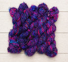 Multiple skeins of Jewel Tones recycled sari silk yarn featuring rich purple, pink and blue fibres.