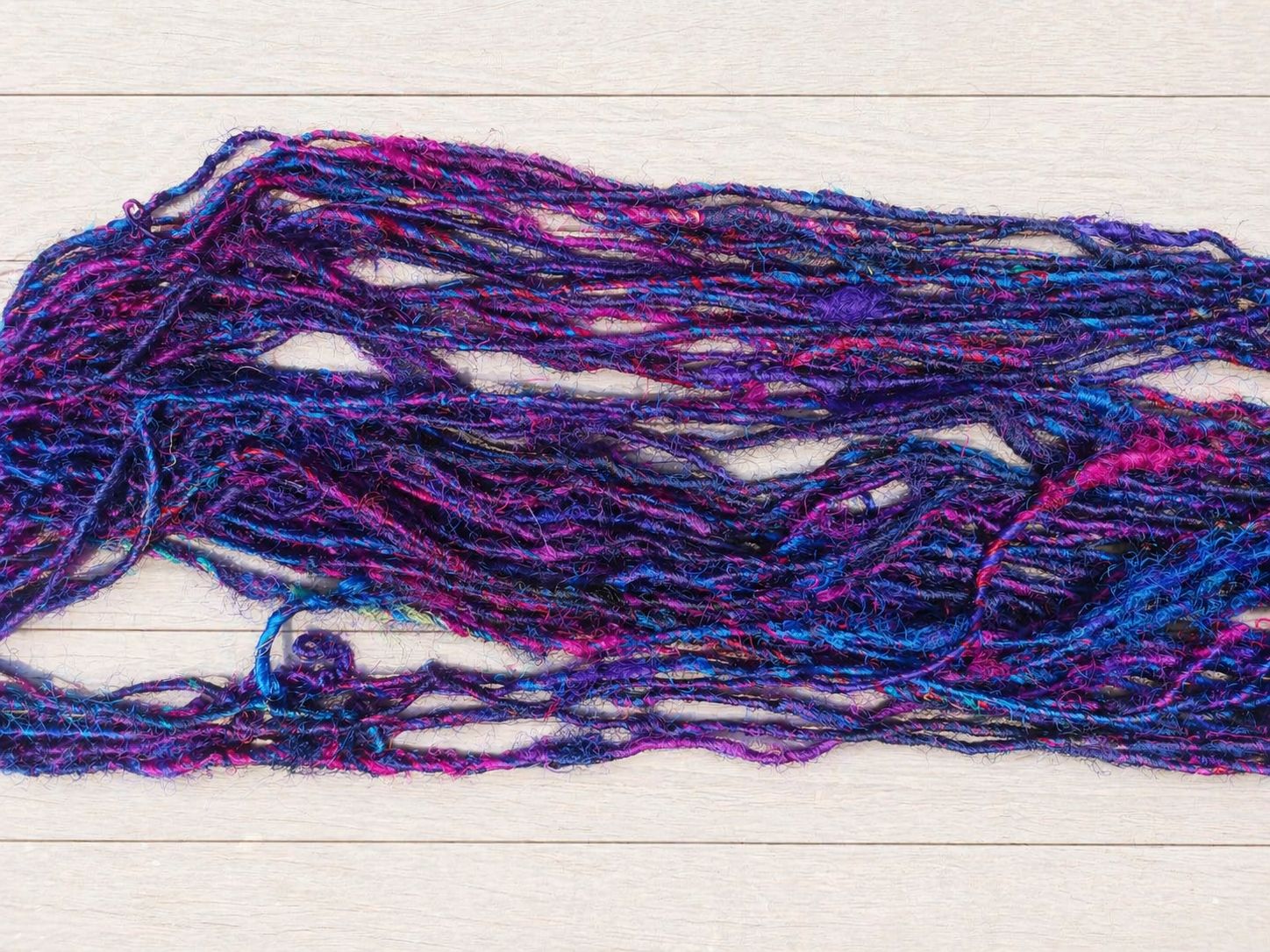 Close-up of Jewel Tones recycled sari silk yarn showing textured handspun fibres and vibrant jewel-tone colours.