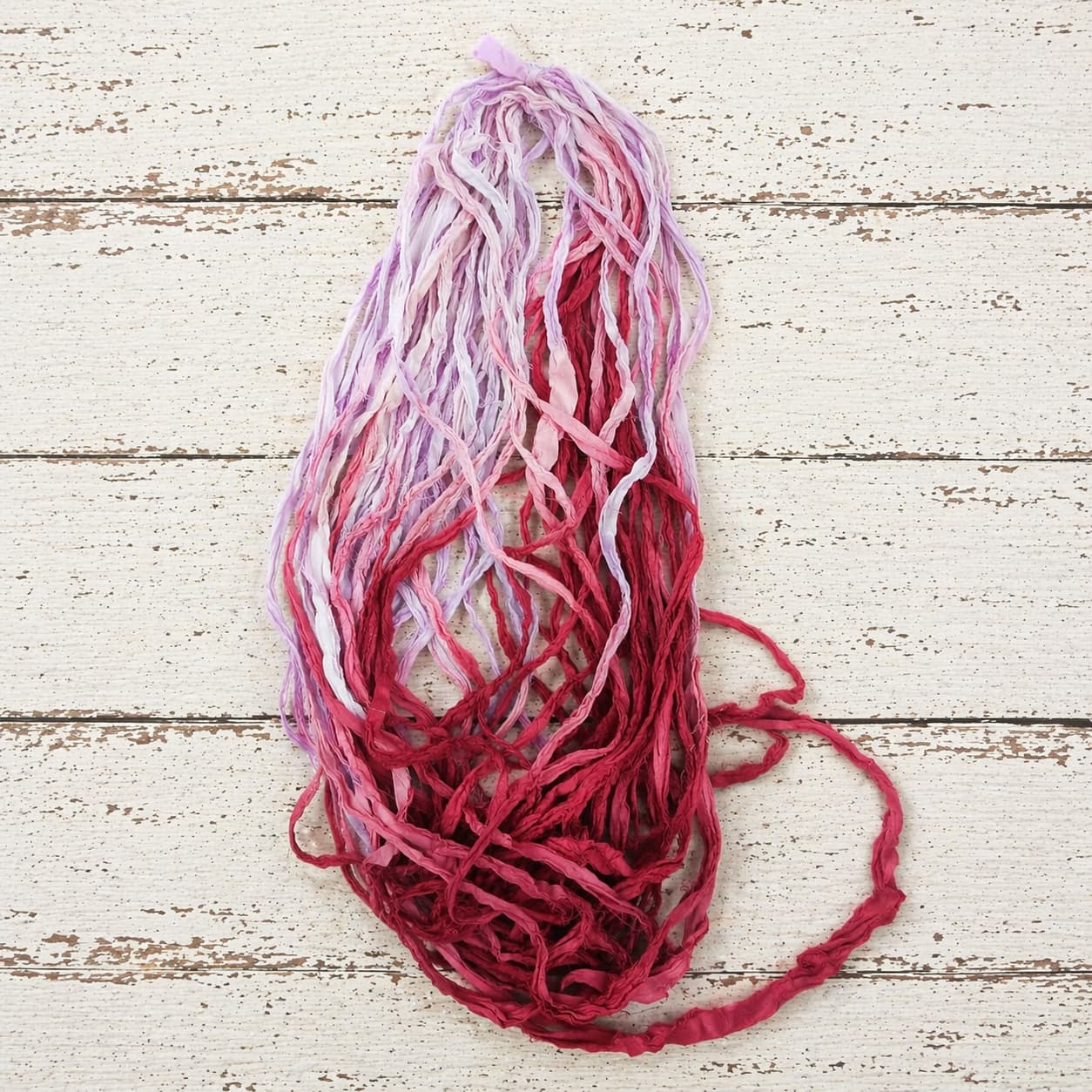 Loose strands of Berry Blossom recycled sari silk ribbon yarn